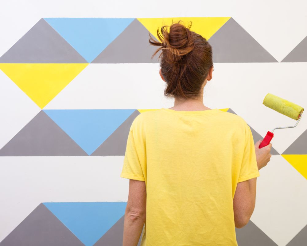 Una chica que está pintando una pared.